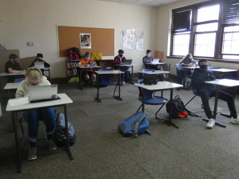 A British Literature class at MacDuffie in November 2020 taking precautions against the spread of COVID-19: face masks, distanced desks, and cracked windows for ventilation.